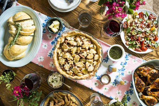 Abundant late summer spread with cardamom apple pie, paprika chicken, basil tomato salad, garlic challah and fried okra — Stock Photo
