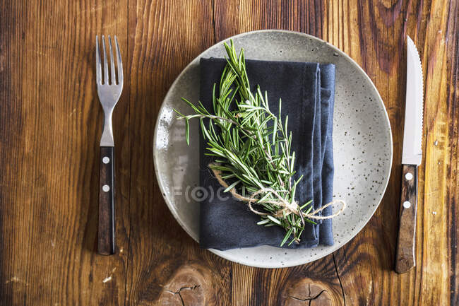 Tavola rustica con piatto in ceramica decorato con tovagliolo e rosmarino — Foto stock