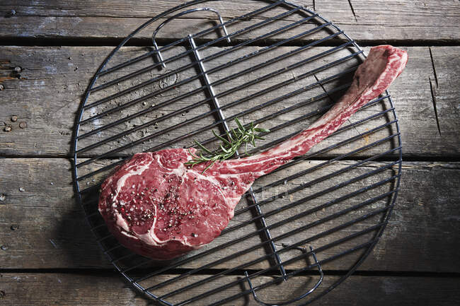 Raw tomahawk steak on a grill grid — Stock Photo