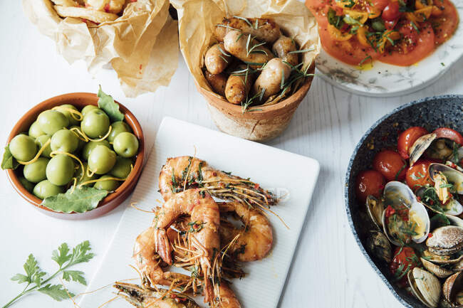 Prawns with chilli and garlic, clams with tomatoes, onion rings and olives — Stock Photo