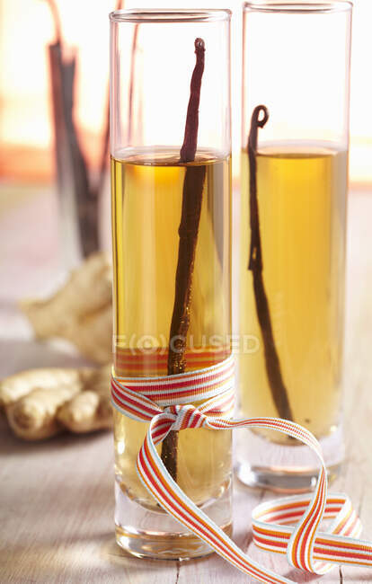 Homemade vanilla and ginger vinegar in cylindrical glasses with a bow — Stock Photo