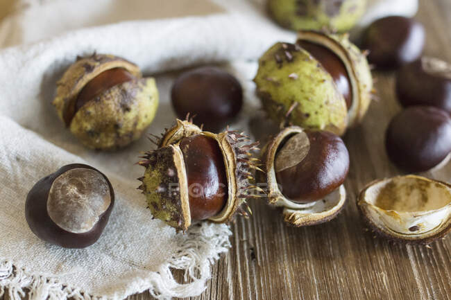 Horse chestnuts with cases on a wooden surface — Stock Photo