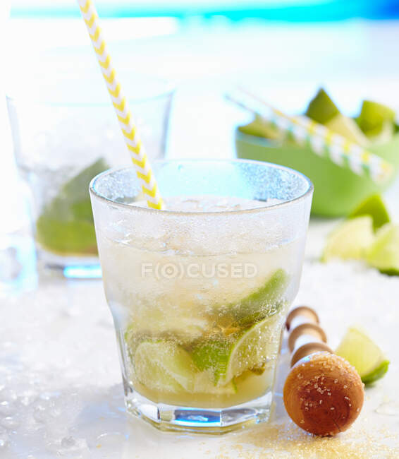Caipirinha with ginger ale and limes served with straw in glass — Stock Photo