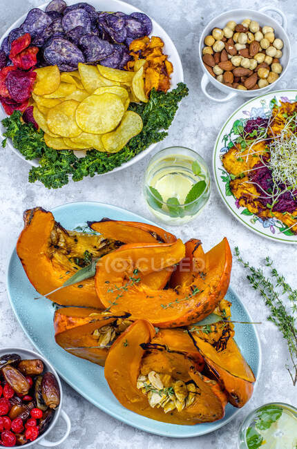 Vegan food, baked pumpkin with sage, germinated seeds and chips from two kinds of potatoes, pumpkin, beetroot and kale, dried fruits and nuts — Stock Photo