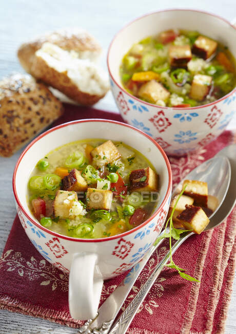 Sopa de mijo vegetal con tofu ahumado servido en tazas - foto de stock
