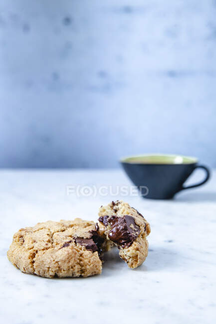 Cookie with chocolate chips and cup of coffee on background — Stock Photo