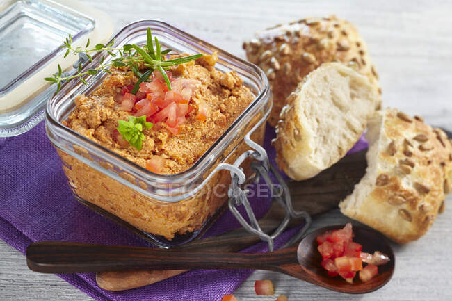 Tofu and tomato spread in a glass jar served with bread rolls — Stock Photo