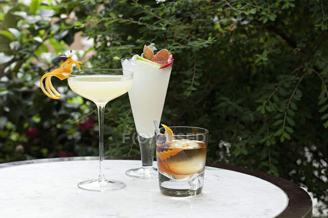Набор из трех коктейлей на столе в саду — стоковое фото