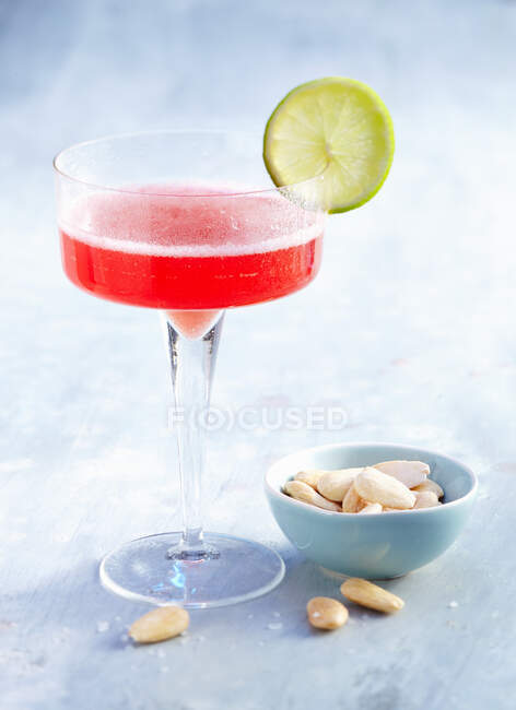 Prosecco Campari cocktail served with lime slice and salted almonds — Stock Photo