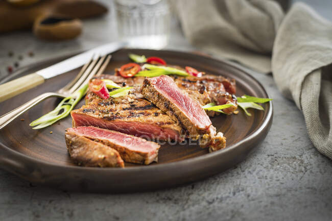 A grilled beefsteak sprinkled with chili and spring onion — Stock Photo
