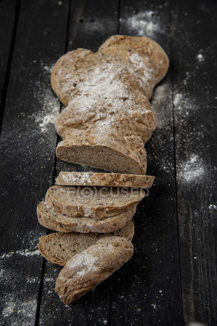 A long loaf of flax seed wholemeal bread, sliced — Stock Photo