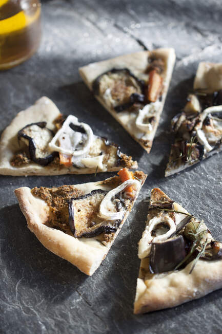 Pizza topped with eggplant, goat's cheese, rosemary, red pepper and green olives — Stock Photo