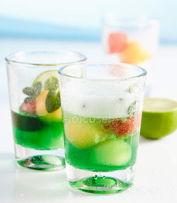 Melon and mint alcohol punch served in glasses with melon balls and strawberries — Stock Photo