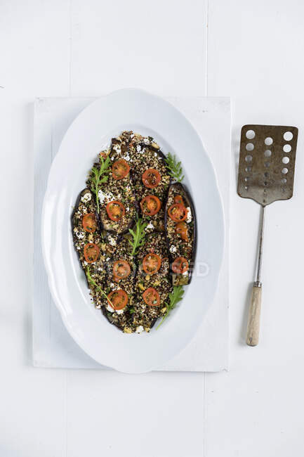 This is a baked aubergine dish topped with a mix of quinoa, fresh herbs and feta cheese (gluten free) — Stock Photo