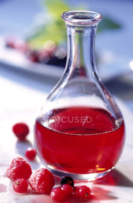 Vinagre casero de bayas rojas en una botella de vidrio - foto de stock