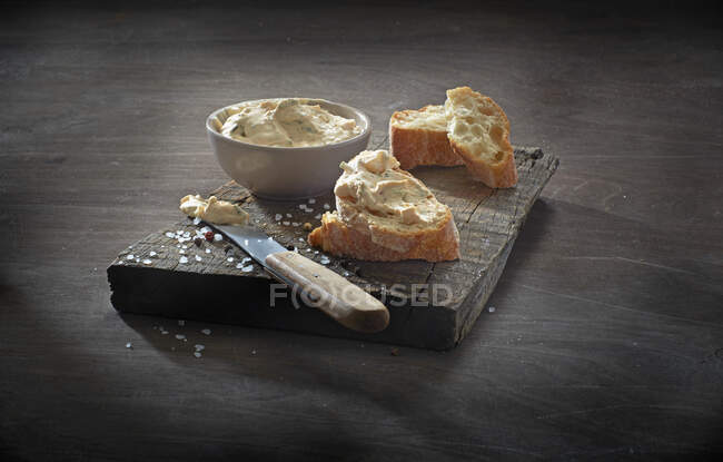 Взбитые сливки сыра в миске и на ломтиках багета — стоковое фото