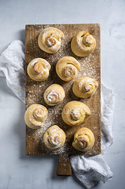 Vegan yeast spirals dusted with icing sugar on a wooden board (seen from above) — Stock Photo