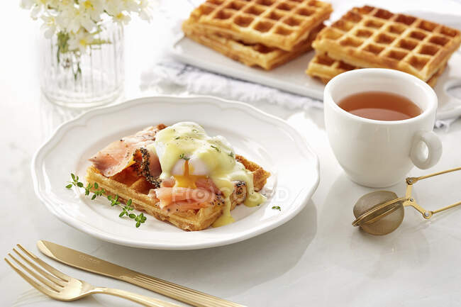 Waffle com salmão defumado, ovo escalfado aberto e molho — Fotografia de Stock