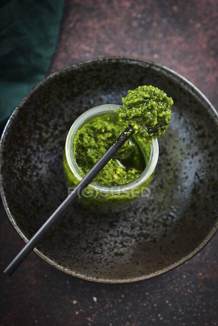 Pesto vert dans un bocal fond sombre — Photo de stock