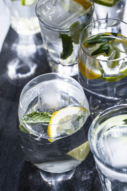 Glasses of drinks with lemons, limes, mint and ginger — Stock Photo