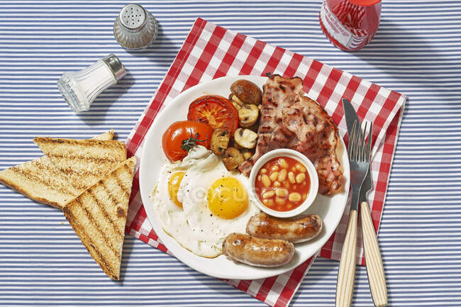 Завтрак с яичницей и беконом на тарелке — стоковое фото