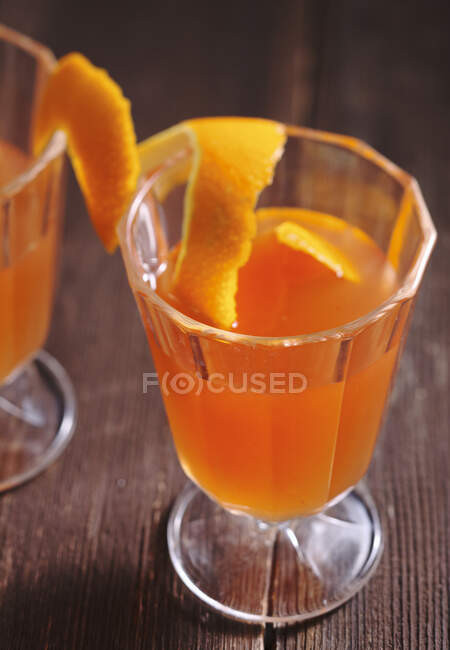 Homemade red grapefruit syrup with zest in glasses on wooden table — Stock Photo