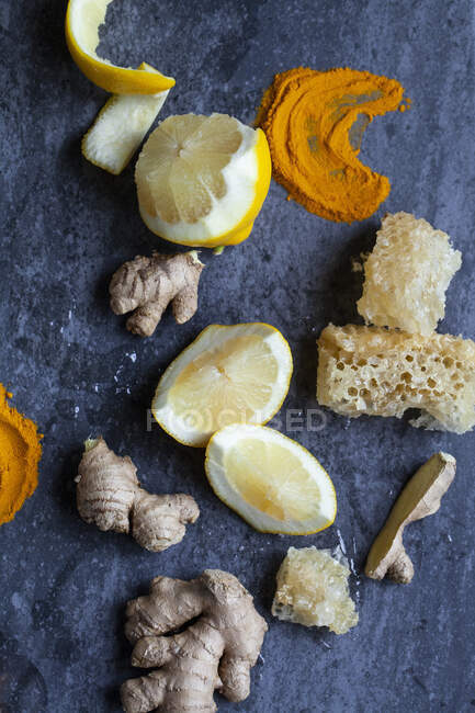 Lemon, turmeric powder, ginger, and honeycomb on a blue surface — Stock Photo