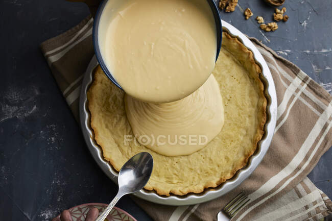 Primer plano de delicioso relleno de mascarpone verter en cáscara de tarta. - foto de stock