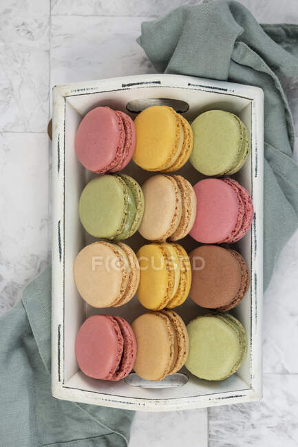 Colorful macarons in white wooden crate — Stock Photo