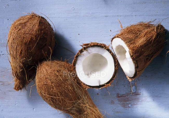 Primer plano de deliciosos cocos, enteros y cortados a la mitad - foto de stock