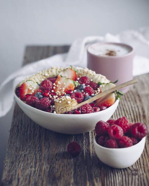 Una ciotola di porridge con frutta, caffè e lamponi — Foto stock