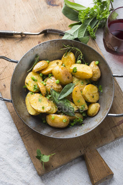 Patatas nuevas caramelizadas con guisantes y hierbas frescas - foto de stock
