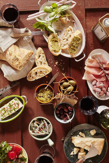 Bruschetta with pesto, mini salami, olives, Parmesan, olive oil, giant capers and red wine — Stock Photo
