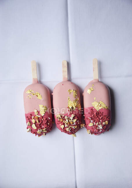 Three pink ice cream sticks with gold leaf — Stock Photo