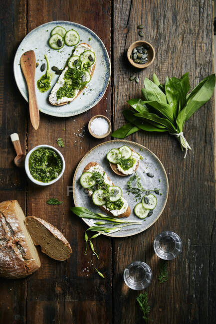 Bread with wild garlic pesto, cream cheese and cucumber on a wooden background — Stock Photo
