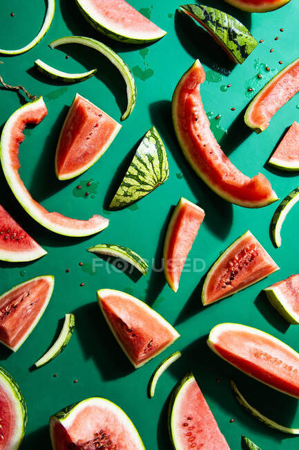 Fatias de melancia fresca, inteiras, comidas e cascas em fundo verde — Fotografia de Stock