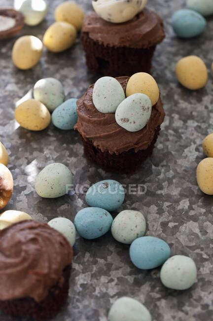 Chocolate cupcakes with mini chocolate eggs on a textured surface — Stock Photo