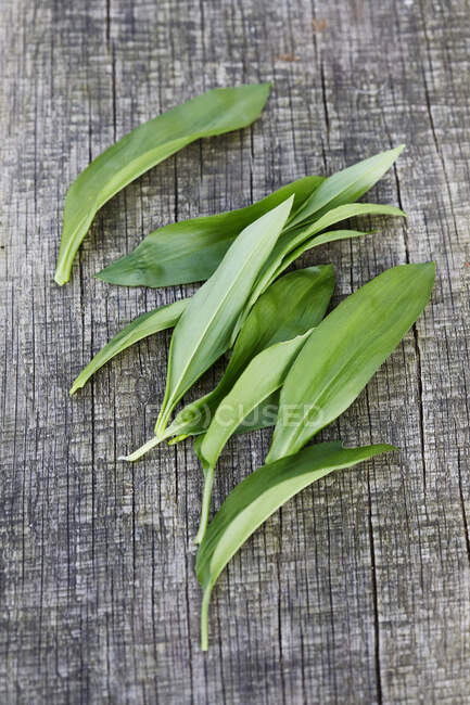 Several wild garlic leaves on wooden surface — Stock Photo