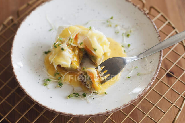 Huevos Benedict con microgreen y pieza cortada en tenedor - foto de stock