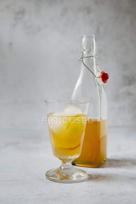 Earl Grey tea with apple slices and ice cubes in a glass and in a bottle — Stock Photo