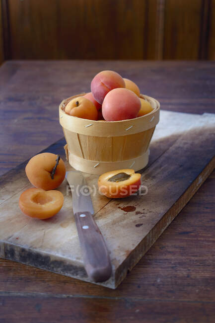 Aprikosen im Holzkorb und auf Holzbrett mit Messer — Stockfoto
