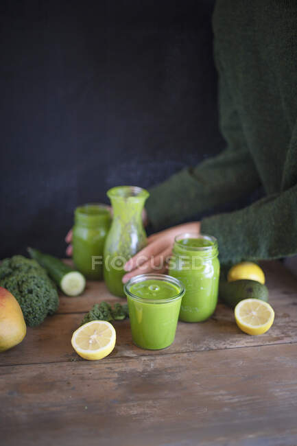 Un frullato verde con ingredienti su un tavolo di legno rustico — Foto stock