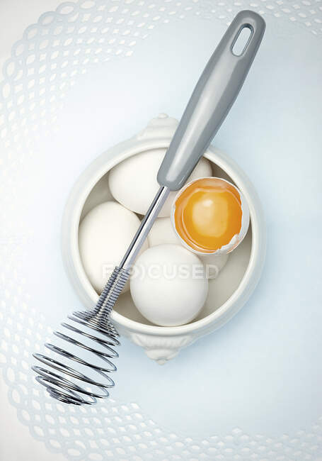 Uova e una frusta — Foto stock