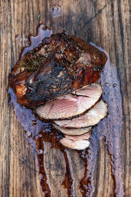 Grilled leg of lamb, sliced on rustic wooden surface — Stock Photo