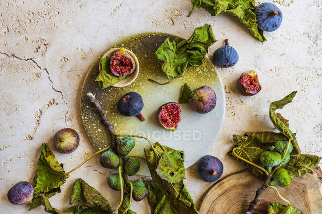 Figues fraîches avec feuilles de figuier sur la surface rustique — Photo de stock