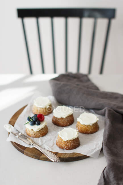 Cardamom and marzipan cakes topped with cream and berries — Stock Photo