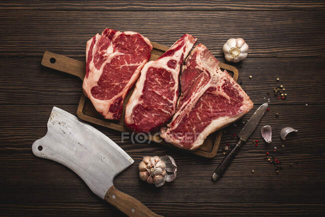 Raw rib-eye steak, a T-bone steak and a cowboy steak — Stock Photo