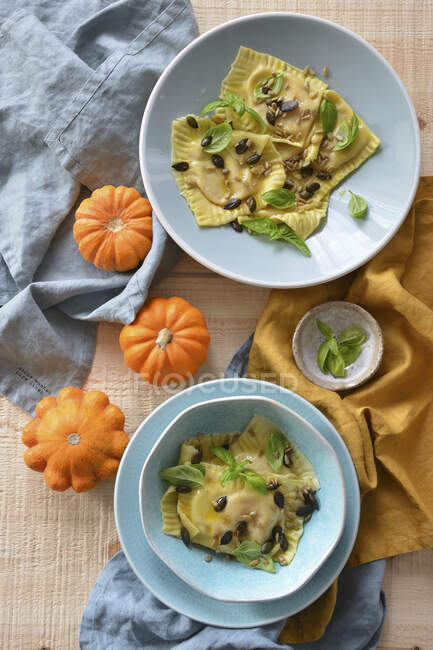 Ravioli with pumpkin and ricotta served with seeds and basil leaves — Stock Photo