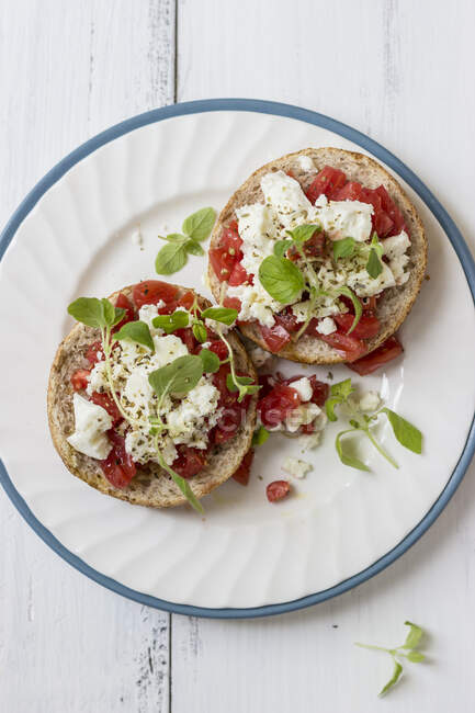 Open sandwiches with chopped tomatoes, feta and oregano on special bread — Stock Photo