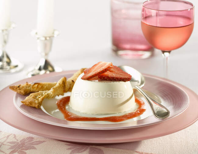 Strawberry panna cotta with a filo pastry twist and coulis with a glass of rose wine — Stock Photo